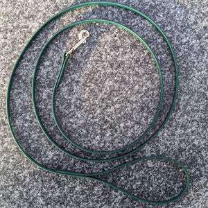 A thin forest green Biothane dog leash with a metal snap clip, laid out on a grey surface.